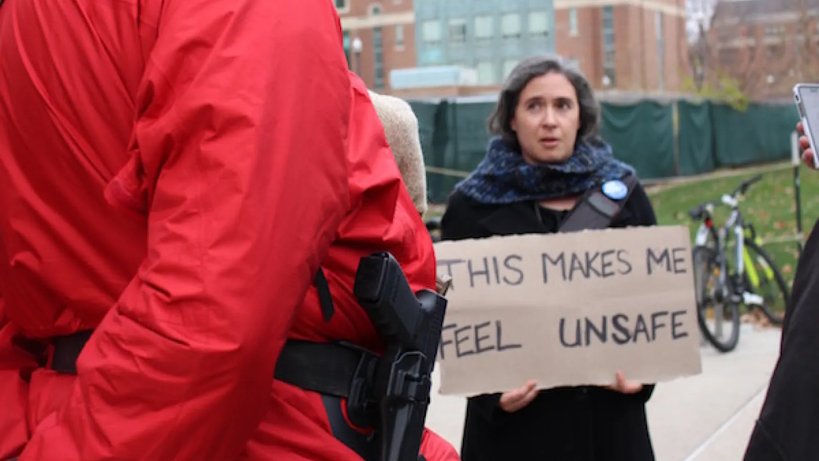 Merrill Kaplan holds a sign saying, "This makes me feel unsafe"