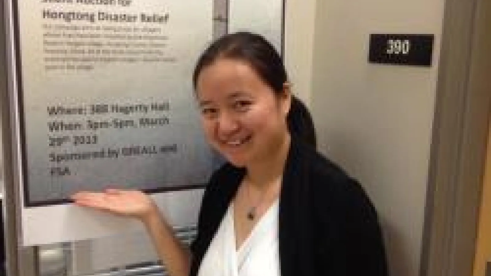 Ziying You posing in front of her Silent Auction promotional flier