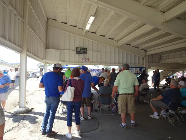 Attendees watch the races below the Grandstand on a mounted television screen.