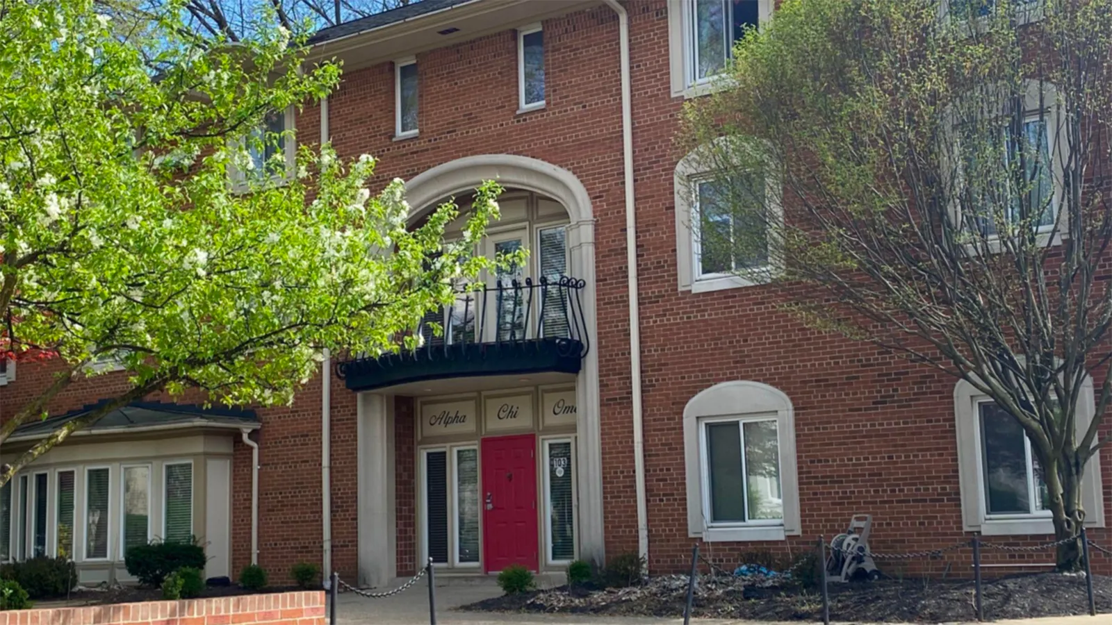 A large brick building with a red door and a balcony above it